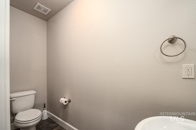 bathroom with toilet, a sink, visible vents, and baseboards