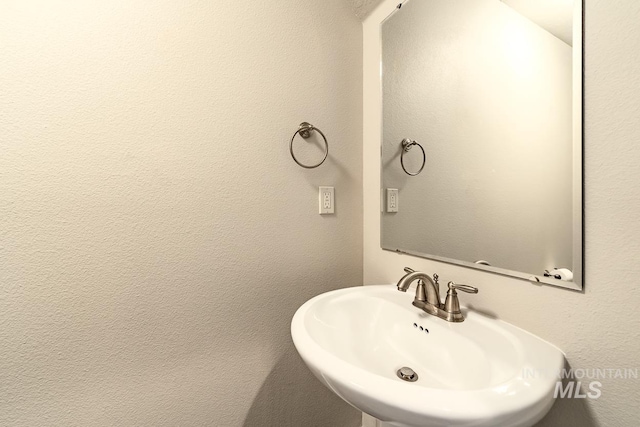 bathroom featuring a textured wall and a sink