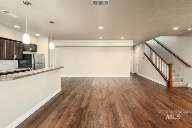 unfurnished living room featuring stairs, dark wood-style flooring, and visible vents