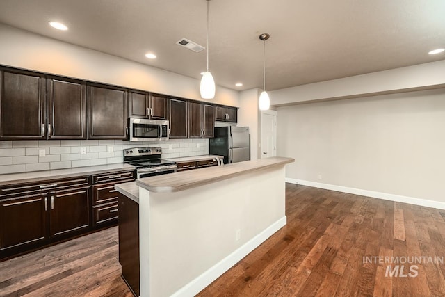 kitchen with dark wood-style floors, appliances with stainless steel finishes, backsplash, and visible vents