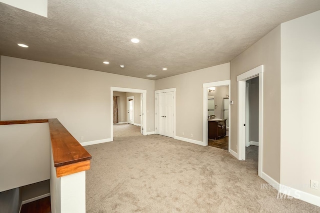 unfurnished bedroom with baseboards, a textured ceiling, carpet, and recessed lighting