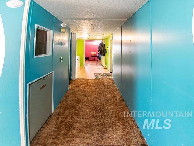 hallway featuring light carpet and a textured ceiling