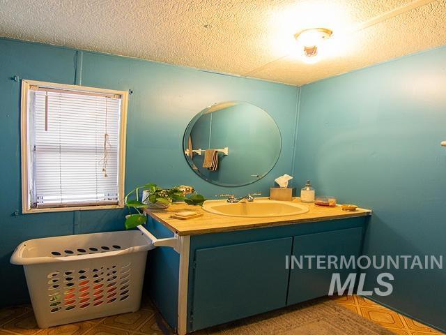 bathroom featuring vanity, plenty of natural light, a bath, and a textured ceiling