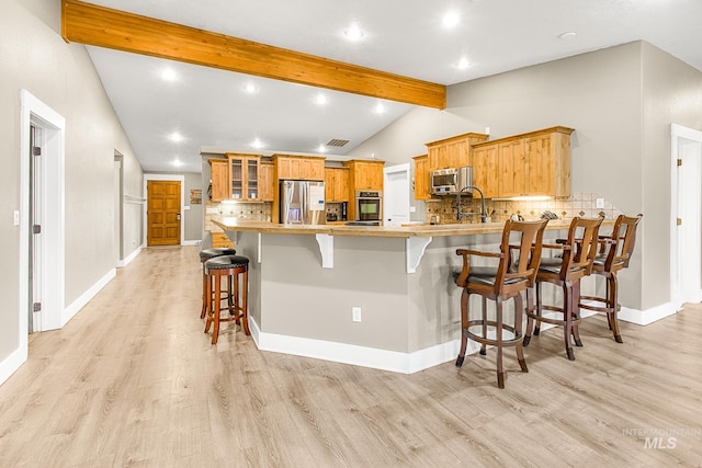 kitchen featuring stainless steel appliances, a kitchen bar, kitchen peninsula, and tasteful backsplash