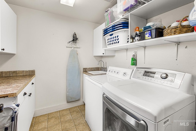 laundry area featuring washing machine and dryer, cabinets, sink, and light tile patterned flooring