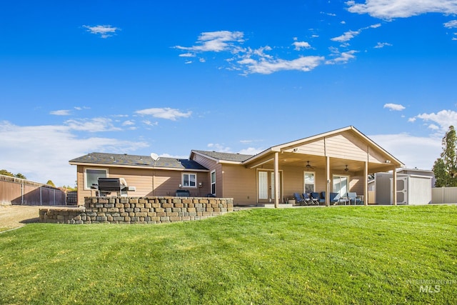 rear view of property featuring a storage unit, a patio, a lawn, and ceiling fan