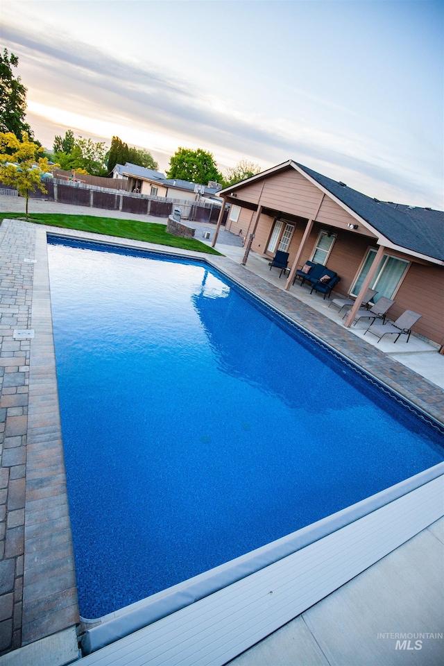 pool at dusk with a patio area