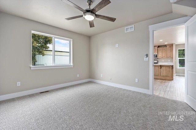 empty room featuring light colored carpet and ceiling fan