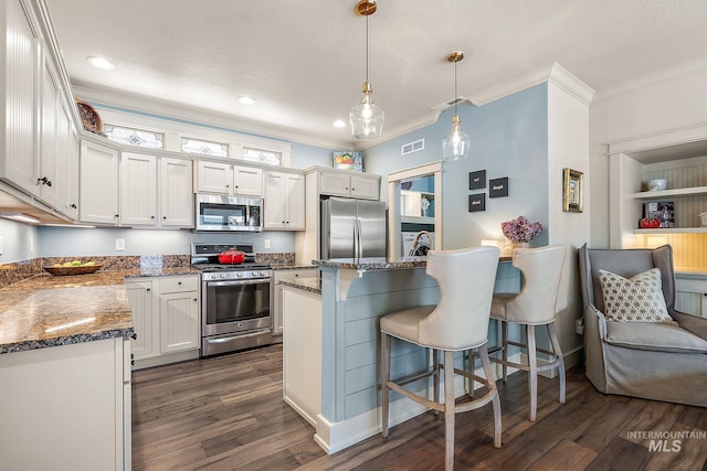 998 E Shadow Creek Ln, Eagle, ID 83616 - kitchen with appliances with stainless steel finishes, dark wood-style floors, ornamental molding, a kitchen breakfast bar, and white cabinetry