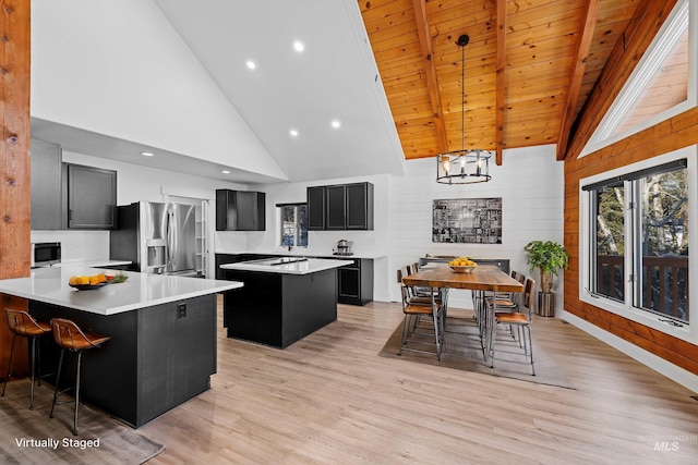 kitchen featuring beamed ceiling, hanging light fixtures, a center island, wood ceiling, and stainless steel appliances