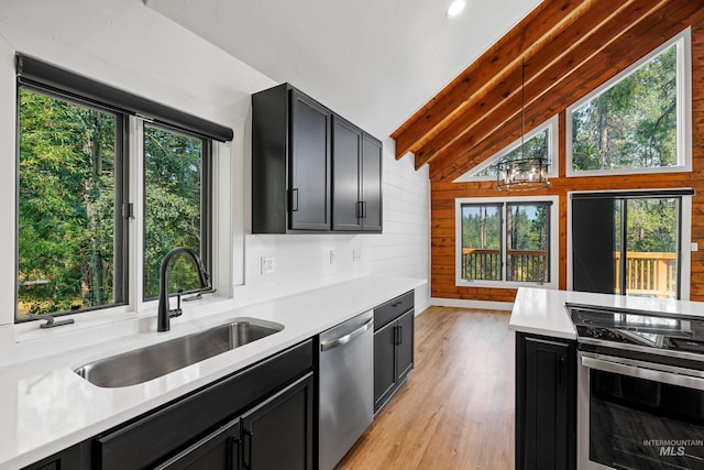 kitchen with sink, appliances with stainless steel finishes, light hardwood / wood-style floors, beamed ceiling, and wood walls