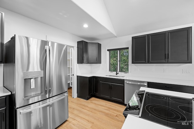 kitchen featuring appliances with stainless steel finishes, sink, lofted ceiling, and light wood-type flooring