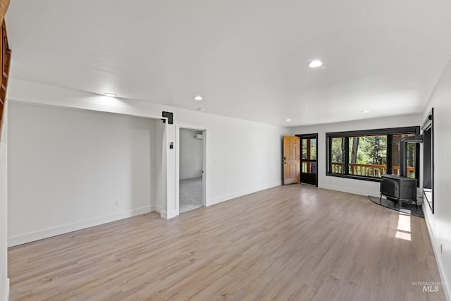 unfurnished living room with light wood-type flooring and a wood stove