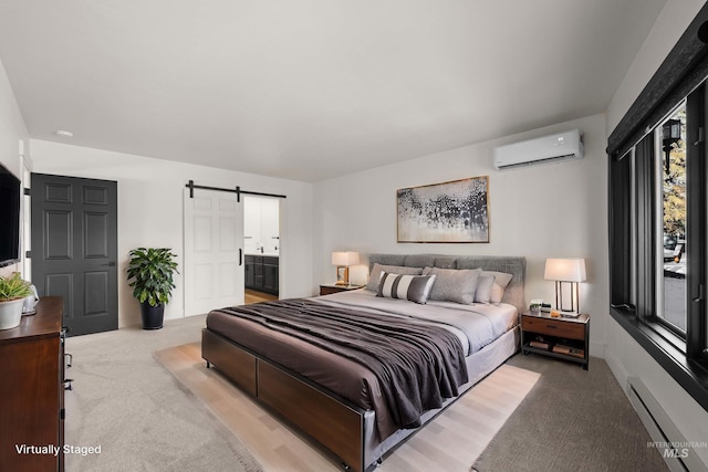 bedroom with ensuite bathroom, a baseboard radiator, a barn door, light carpet, and a wall unit AC