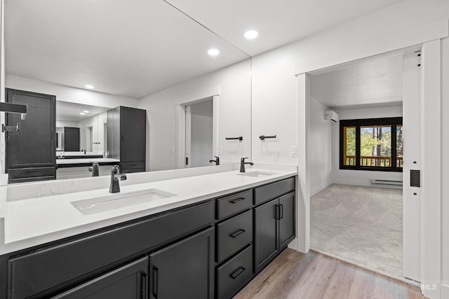 bathroom featuring baseboard heating, vanity, hardwood / wood-style flooring, and an AC wall unit