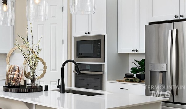 2386 N Ice Fire Ave, Star, ID 83669 - kitchen featuring appliances with stainless steel finishes, a sink, white cabinets, backsplash, and light countertops