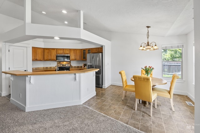 kitchen featuring appliances with stainless steel finishes, brown cabinetry, a chandelier, glass insert cabinets, and recessed lighting