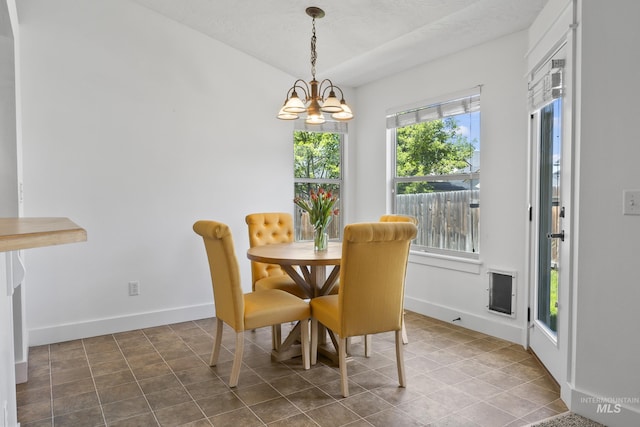 tiled dining space with a chandelier and baseboards