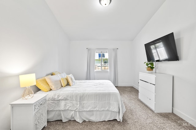 bedroom featuring lofted ceiling, light colored carpet, and baseboards