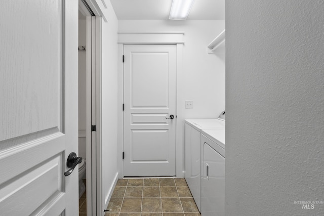 laundry area featuring washing machine and clothes dryer and a textured wall