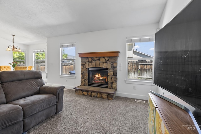 living area featuring baseboards, a fireplace, a chandelier, and carpet floors