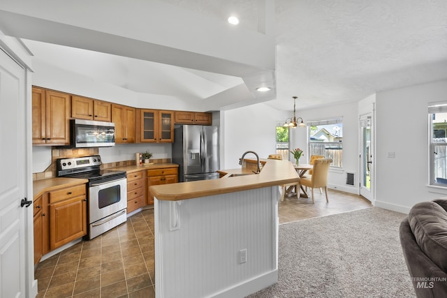 kitchen featuring appliances with stainless steel finishes, a sink, brown cabinetry, plenty of natural light, and recessed lighting
