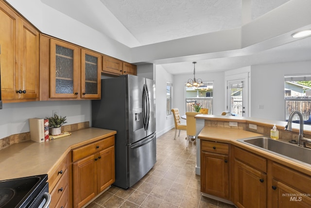 kitchen featuring a sink, brown cabinets, stainless steel refrigerator with ice dispenser, vaulted ceiling, and dark tile patterned floors