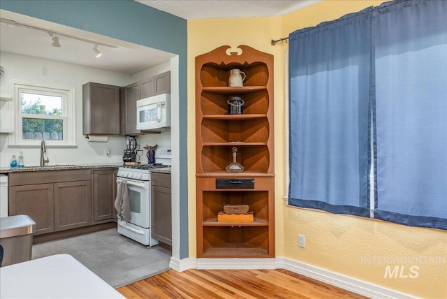 kitchen featuring white appliances, light wood-style floors, a sink, and open shelves