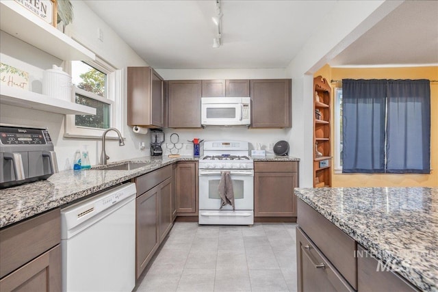 kitchen with white appliances, a sink, open shelves, light stone countertops, and light tile patterned floors