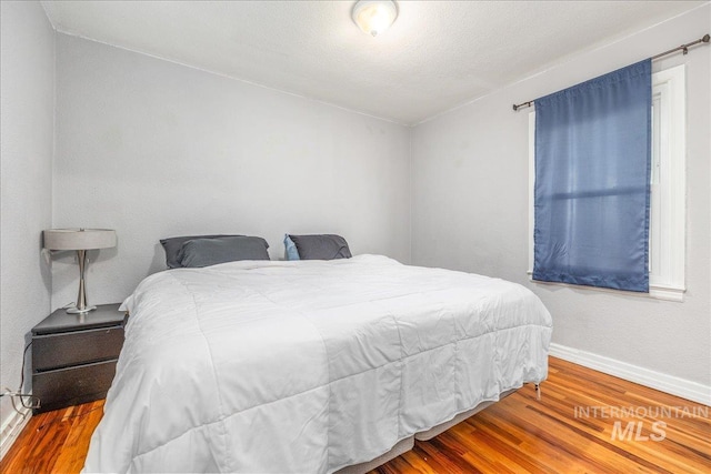 bedroom with baseboards and wood finished floors