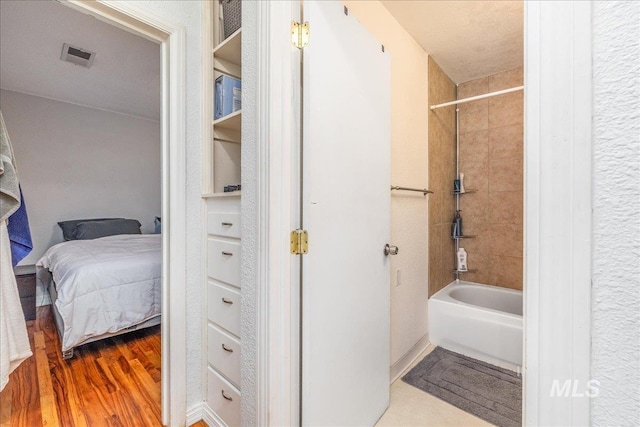 full bath with bathing tub / shower combination, wood finished floors, and ensuite bath
