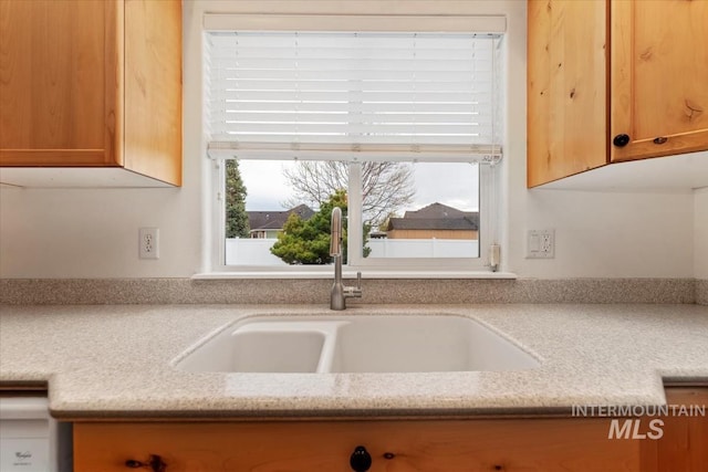 interior space featuring brown cabinetry, light stone counters, and a sink