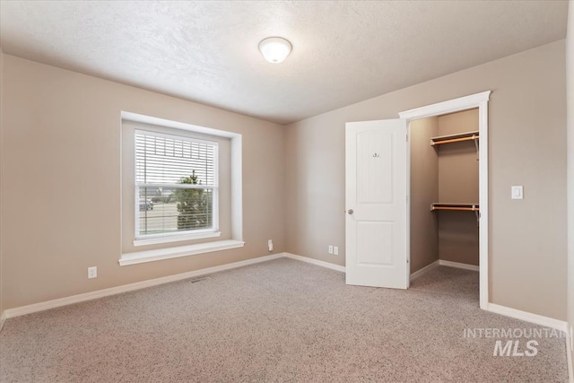 unfurnished bedroom with a closet, baseboards, a walk in closet, and carpet