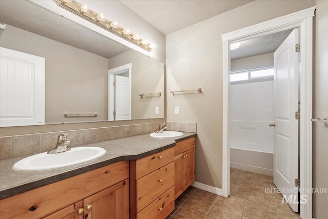full bathroom featuring tile patterned flooring, double vanity, a tub, and a sink