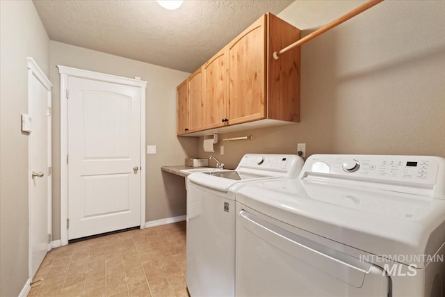 laundry room with a textured ceiling, washing machine and dryer, baseboards, and cabinet space