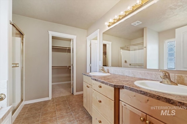 full bath featuring a shower stall, a walk in closet, visible vents, and a sink