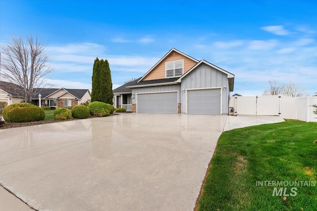 view of front facade featuring board and batten siding, fence, a front lawn, a gate, and driveway