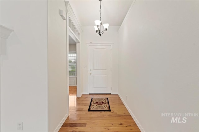 entryway with baseboards, a notable chandelier, and light wood-style floors