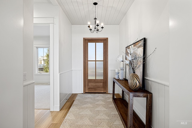 entryway with light wood-type flooring, an inviting chandelier, and wood ceiling