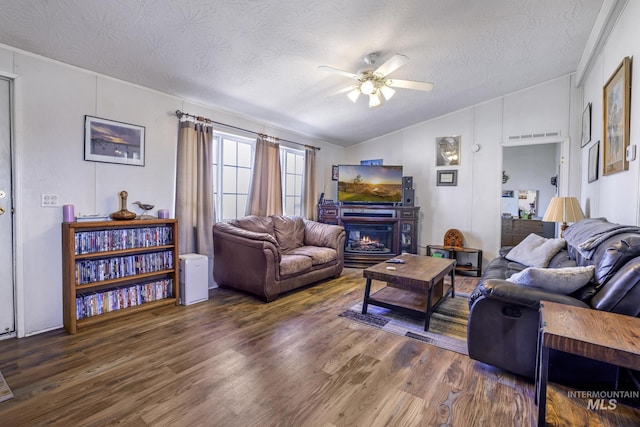 living room with vaulted ceiling, a textured ceiling, a ceiling fan, and wood finished floors