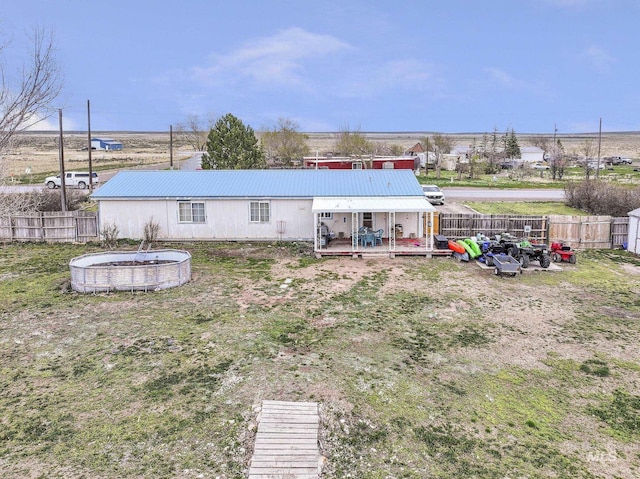 rear view of house featuring a wooden deck, a fenced backyard, and metal roof