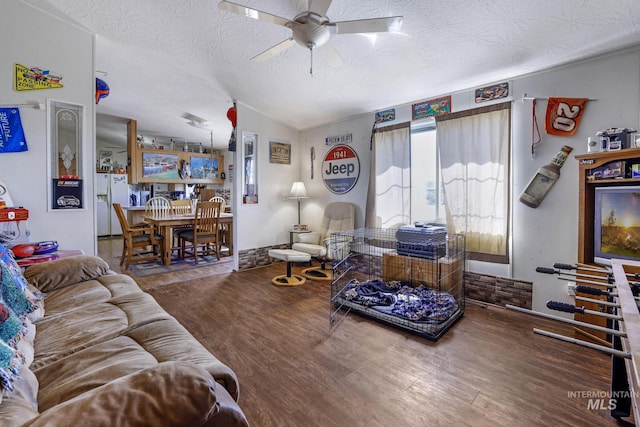 living room featuring vaulted ceiling, wood finished floors, a textured ceiling, and ceiling fan