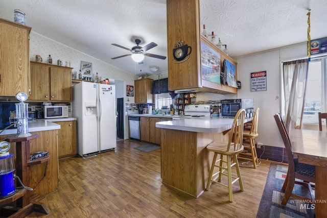 kitchen featuring lofted ceiling, white appliances, and brown cabinets