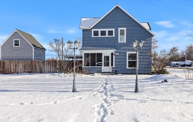 snow covered rear of property with a sunroom