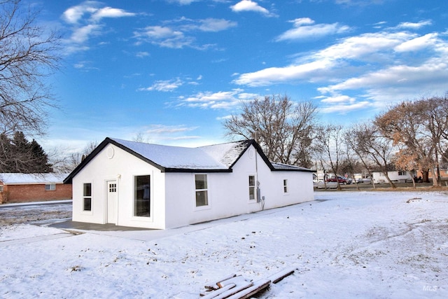 snow covered property with stucco siding