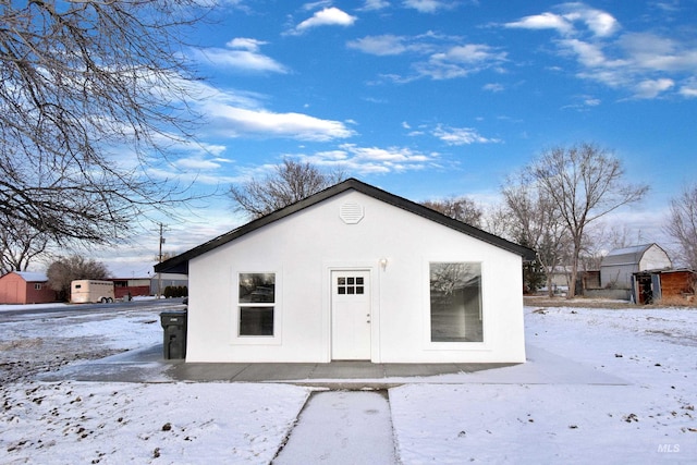 exterior space featuring an outbuilding, stucco siding, and a storage unit