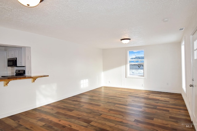 empty room with a textured ceiling, dark wood-type flooring, and baseboards