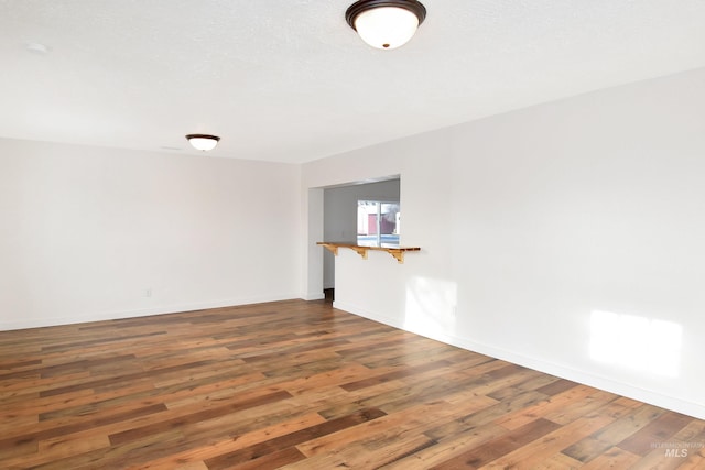 empty room with baseboards and hardwood / wood-style flooring