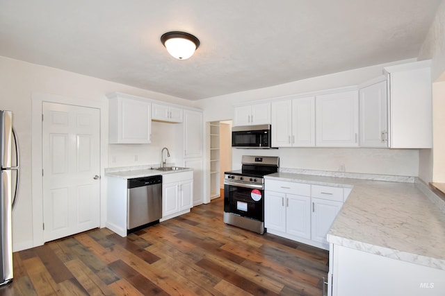 kitchen featuring dark wood finished floors, light countertops, white cabinets, stainless steel appliances, and a sink