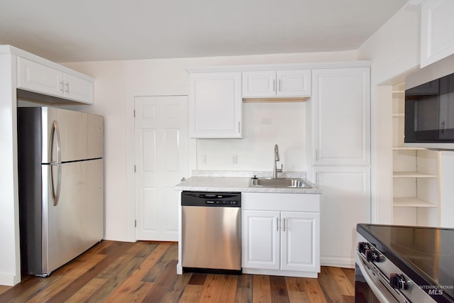 kitchen with dark wood finished floors, white cabinetry, stainless steel appliances, and a sink